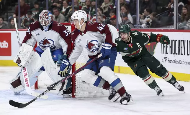 Colorado Avalanche defenseman Josh Manson, center, skates with the puck as Minnesota Wild right wing Mats Zuccarello defends, right, during the second period of an NHL hockey game Thursday, Jan. 9, 2025, in St. Paul, Minn. (AP Photo/Matt Krohn)