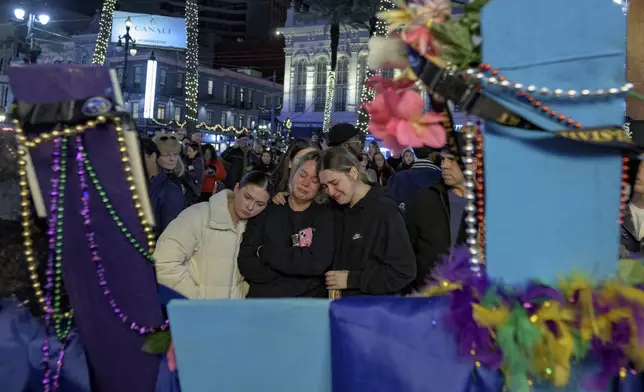 Mourners react next to crosses memorializing the victims of the New Year's Day deadly truck attack and shooting along Canal Street near the intersection of Bourbon Street in New Orleans, Saturday, Jan. 4, 2025. (AP Photo/Matthew Hinton)