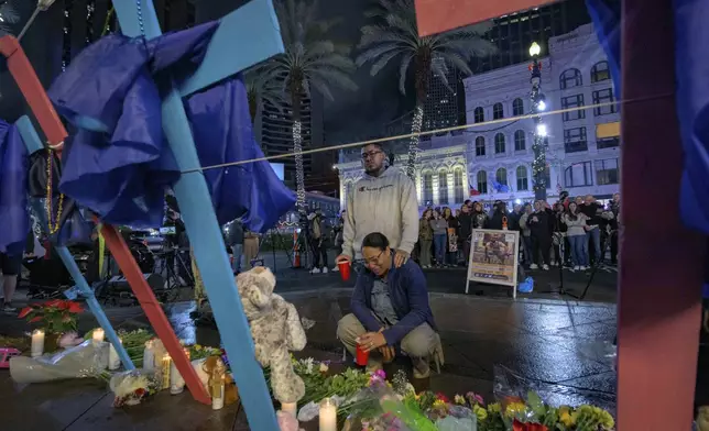 Mourners react next to crosses memorializing the victims of the New Year's Day deadly truck attack and shooting along Canal Street near the intersection of Bourbon Street in New Orleans, Saturday, Jan. 4, 2025. (AP Photo/Matthew Hinton)