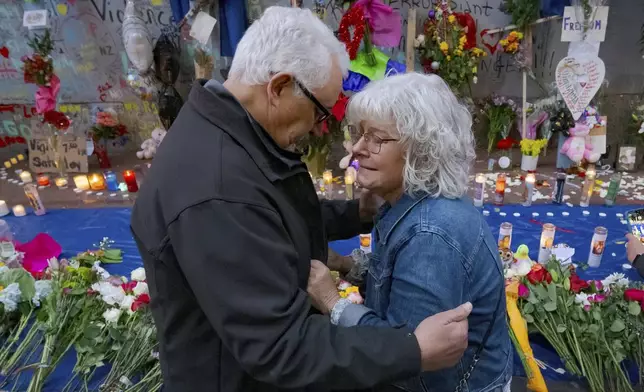 Long Island, New York residents Louis Tenedorio, left, and his wife, Cathy Tenedorio, embrace on by a memorial Bourbon Street and Canal Street in New Orleans, Saturday, Jan. 4, 2025, where their son, Matthew Tenedorio, was killed as one of the victims of the New Year's Day deadly truck attack and shooting. (AP Photo/Matthew Hinton)