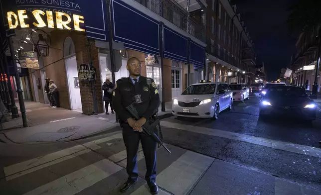 A New Orleans Police officer carries an assault rifle as he stands guard on Bourbon Street during a parade memorializing the victims of the New Year's Day deadly truck attack and shooting in New Orleans, Saturday, Jan. 4, 2025. (AP Photo/Matthew Hinton)