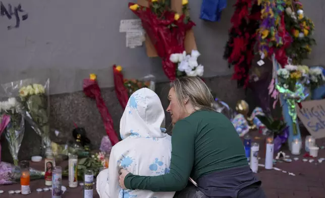 Kelli Galle, right, hugs her son Parker, left, as they visit a memorial to the victims of a deadly truck attack on Bourbon Street in the French Quarter, Friday, Jan. 3, 2025, in New Orleans. (AP Photo/George Walker IV)