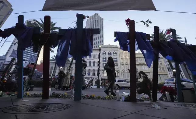 People walk past a memorial on Canal Street for the victims of a deadly truck attack on New Year's Day in New Orleans, Friday, Jan. 3, 2025. (AP Photo/Gerald Herbert)