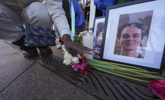 A woman places flowers next to photos of victim Matthew Tenedorio at memorial on Canal Street for the victims of a deadly truck attack on New Year's Day in New Orleans, Friday, Jan. 3, 2025. (AP Photo/Gerald Herbert)