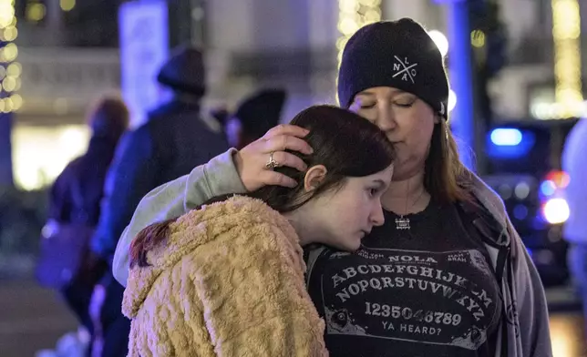 Mourners react next to crosses memorializing the victims of the New Year's Day deadly truck attack and shooting along Canal Street near the intersection of Bourbon Street in New Orleans, Saturday, Jan. 4, 2025. (AP Photo/Matthew Hinton)