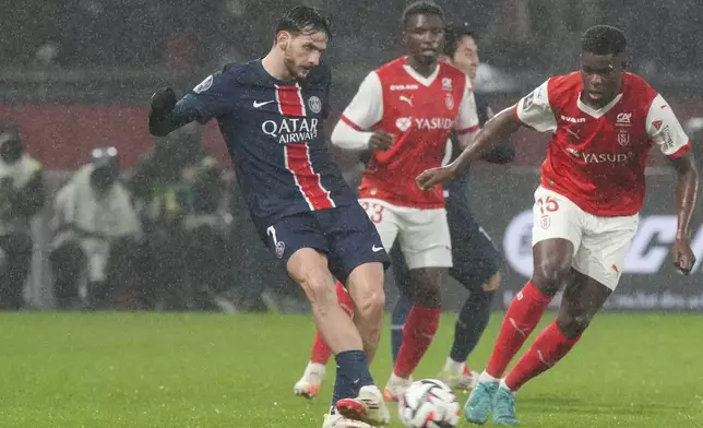 PSG's Khvicha Kvaratskhelia, left, passes the ball during the French League One soccer match between Paris Saint-Germain and Reims at Parc des Princes stadium in Paris, Saturday, Jan. 25, 2025. (AP Photo/Michel Euler)