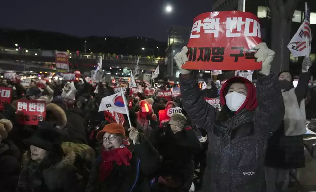 Supporters of impeached South Korean President Yoon Suk Yeol stage a rally to oppose a court having issued a warrant to detain Yoon, as police offices stand guard near the presidential residence in Seoul, South Korea, Friday, Jan. 3, 2025. The sign reads "Oppose Impeachment." (AP Photo/Lee Jin-man)