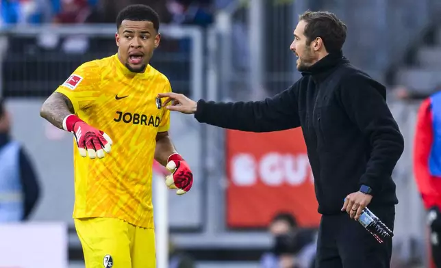 SD Freiburg coach Julian Schuster, right, talks to Freiburg goalkeeper Noah Atubolu before the German Bundesliga soccer match between Freiburg and Holstein Kiel, in in Freiburg im Breisgau, Germany, Saturday, Jan. 11, 2025. (Tom Weller/dpa via AP)