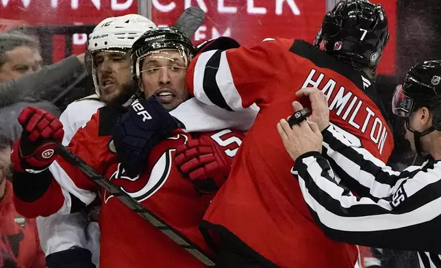 Florida Panthers left wing A.J. Greer and New Jersey Devils defensemen Brenden Dillon and Dougie Hamilton fight during the first period of an NHL hockey game, Tuesday, Jan. 14, 2025, in Newark, N.J. (AP Photo/Julia Demaree Nikhinson)
