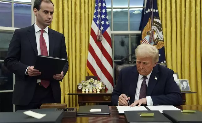 President Donald Trump signs an executive order to create the Department of Government Efficiency (DOGE) in the Oval Office of the White House, Monday, Jan. 20, 2025, in Washington, as White House staff secretary Will Scharf watches. (AP Photo/Evan Vucci)