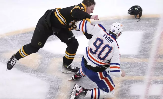 Boston Bruins center Trent Frederic, top, fights Edmonton Oilers right wing Corey Perry (90) during the second period of an NHL hockey game, Tuesday, Jan. 7, 2025, in Boston. (AP Photo/Charles Krupa)