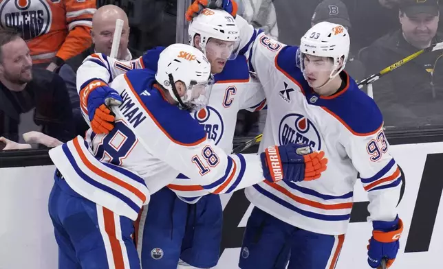 Edmonton Oilers center Connor McDavid, center, is congratulated after his goal against Boston Bruins goaltender Jeremy Swayman during the second period of an NHL hockey game, Tuesday, Jan. 7, 2025, in Boston. (AP Photo/Charles Krupa)