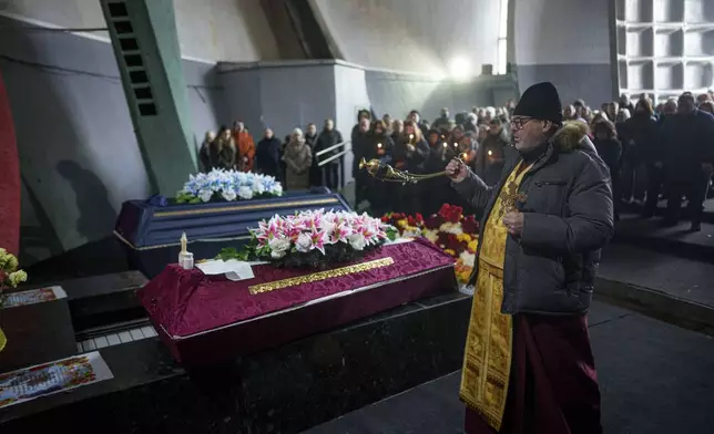 An Orthodox priest performs a funeral service of neurobiologist Ihor Zyma and his wife, biologist Olesia Sokur who were killed by a Russian strike on Jan. 1, in Kyiv, Monday, Jan. 6, 2025. (AP Photo/Evgeniy Maloletka)