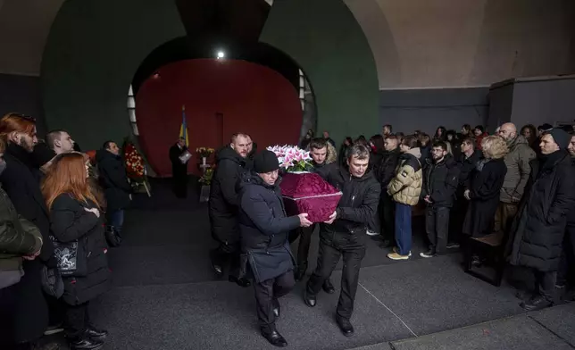 Cemetery workers carry a coffin of biologist Olesia Sokur, who was killed together with her husband neurobiologist Ihor Zyma by a Russian strike on Jan. 1, during a funeral ceremony in Kyiv, Monday, Jan. 6, 2025. (AP Photo/Evgeniy Maloletka)