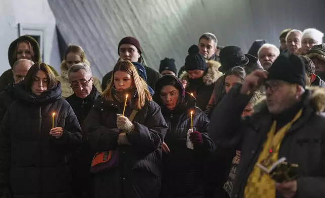 Relatives and friends hold candles during the funeral ceremony of neurobiologist Ihor Zyma and his wife, biologist Olesia Sokur, who were killed by a Russian strike on Jan. 1, in Kyiv, Monday, Jan. 6, 2025. (AP Photo/Evgeniy Maloletka)