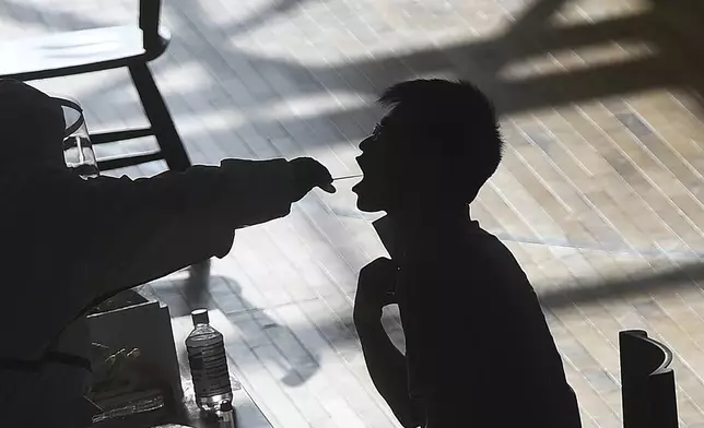 FILE - A medical worker takes a swab sample from a worker of the China Star Optoelectronics Technology (CSOT) company during a round of COVID-19 tests in Wuhan in central China's Hubei province, Aug. 5, 2021. (Chinatopix via AP, File)