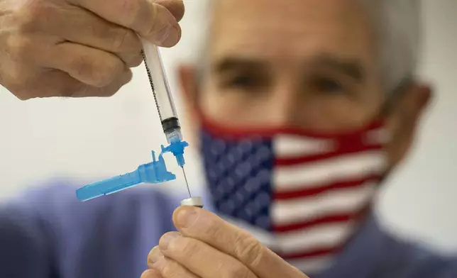 FILE - Dr. Sydney Sewall fills a syringe with the COVID-19 vaccine at the Augusta Armory, Dec. 21, 2021, in Augusta, Maine. (AP Photo/Robert F. Bukaty, File)