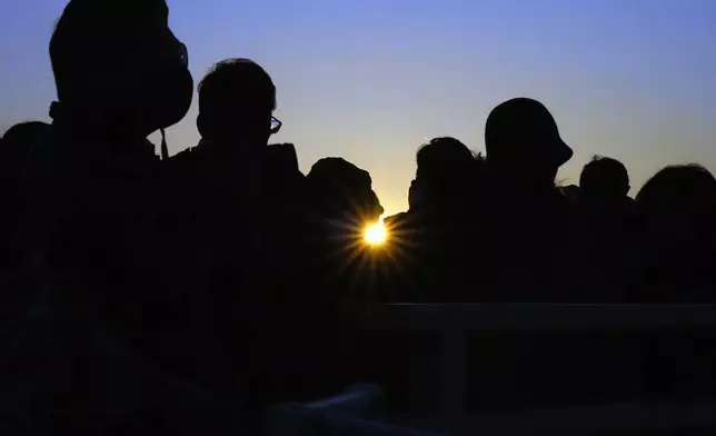 People observe the first sunrise on New Year's Day from a pedestrian bridge, Wednesday, Jan. 1, 2025, in Yokohama near Tokyo. (AP Photo/Eugene Hoshiko)