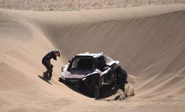 Goncalo Gurreiro and co-driver Cadu Sachs remove their car blocked in the sand during the stage two, day One, of the Dakar Rally with start in Bisha and finish in Bisha, Saudi Arabia, Sunday, Jan. 5, 2025. (AP Photo/Christophe Ena)