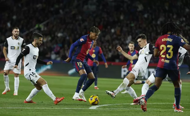 Barcelona's Lamine Yamal, centre, and Valencia's Pepelu, centre right, challenge for the ball during the Spanish La Liga soccer match between Barcelona and Valencia at the Lluis Companys Olympic Stadium in Barcelona, Spain, Sunday, Jan. 26, 2025. (AP Photo/Joan Monfort)