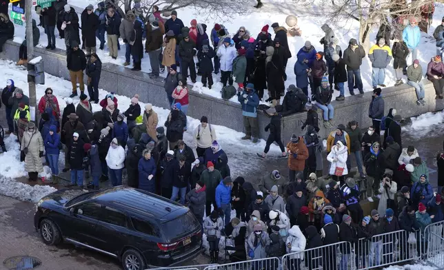 Spectators wait for the casket of former President Jimmy Carter to arrive at the U.S. Navy Memorial before traveling on to the Capitol in Washington, Tuesday, Jan. 7, 2025, where Carter will lie in state. Carter died Dec. 29 at the age of 100. (AP Photo/Mark Schiefelbein, Pool)