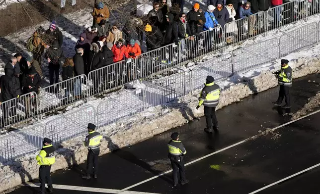 Police look on as spectators wait for the casket of former President Jimmy Carter to arrive at the U.S. Navy Memorial before traveling on to the Capitol in Washington, Tuesday, Jan. 7, 2025, where Carter will lie in state. Carter died Dec. 29 at the age of 100. (AP Photo/Mark Schiefelbein, Pool)