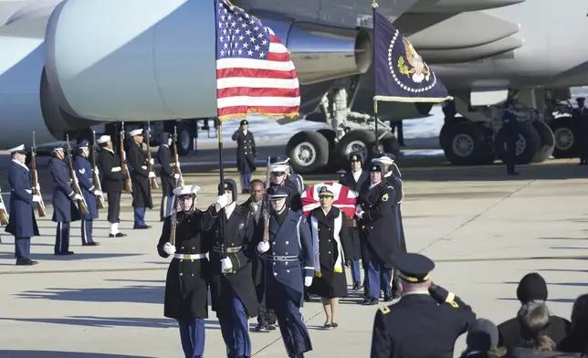 A joint services military body bearer team carries the flag-draped casket of former President Jimmy Carter on arrival at Joint Base Andrews, Md., Tuesday, Jan. 7, 2025, and will travel on to the Capitol where he will lie in State. Carter died Dec. 29 at the age of 100. (AP Photo/Steve Helber)