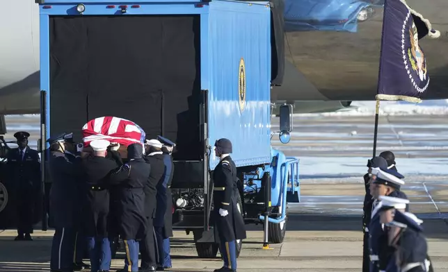 A joint services military body bearer team prepares to carry the flag-draped casket of former President Jimmy Carter on arrival at Joint Base Andrews, Md., Tuesday, Jan. 7, 2025, and will travel to the Capitol where he will lie in State. Carter died Dec. 29 at the age of 100. (AP Photo/Steve Helber)