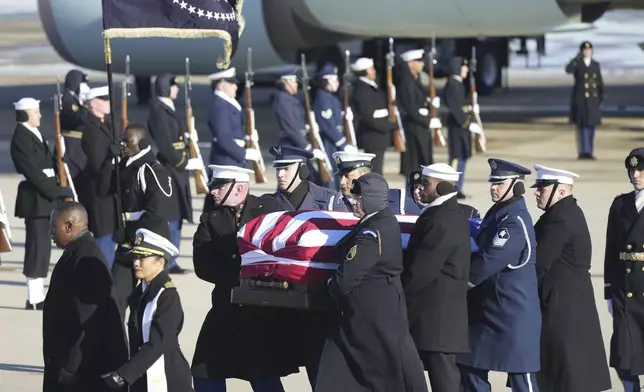 A joint services military body bearer team carries the flag-draped casket of former President Jimmy Carter on arrival at Joint Base Andrews, Md., Tuesday, Jan. 7, 2025, and will travel on to the Capitol where he will lie in State. Carter died Dec. 29 at the age of 100. (AP Photo/Steve Helber)