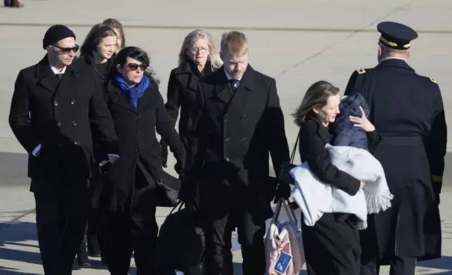 The Carter family walks off a military plane carrying the casket of former President Jimmy Carter, as they arrive at Joint Base Andrews, Md., Tuesday, Jan. 7, 2025. (AP Photo/Steve Helber)