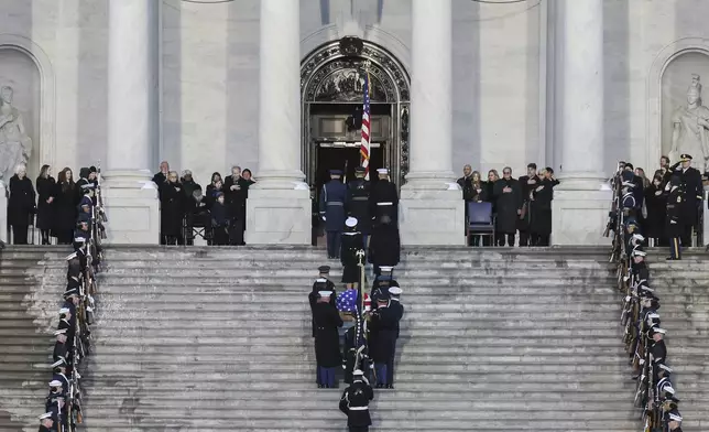 Members of the Carter family look on as a joint services military body bearer team carries the flag-draped casket of former President Jimmy Carter up the steps into the U.S Capitol, Tuesday, Jan. 7, 2025, in Washington. Carter died Dec. 29 at the age of 100. (Jemal Countess/Pool via AP)