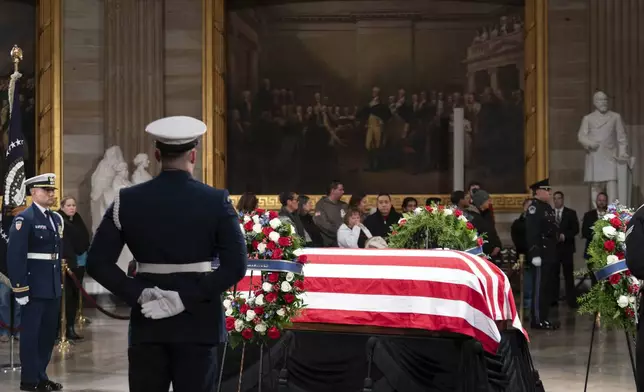 Mourners look at the flag-draped casket of former President Jimmy Carter as he lies in state in the Capitol, Tuesday, Jan. 7, 2025, in Washington. Carter died Dec. 29 at the age of 100. (AP Photo/Jose Luis Magana)