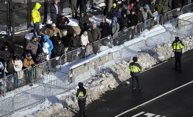 Police look on as spectators wait for the casket of former President Jimmy Carter to arrive at the U.S. Navy Memorial before traveling on to the Capitol in Washington, Tuesday, Jan. 7, 2025, where Carter will lie in state. Carter died Dec. 29 at the age of 100. (AP Photo/Mark Schiefelbein, Pool)