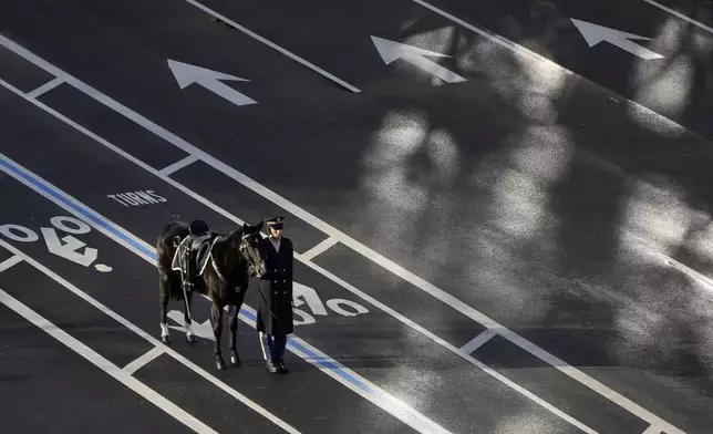 A horse and a member of the military that will transport the caisson carrying former President Jimmy Carter's casket waits at the U.S. Navy Memorial before traveling on to the Capitol in Washington to lie in state, Tuesday, Jan. 7, 2025. Carter died Dec. 29 at the age of 100. (AP Photo/Mark Schiefelbein, Pool)