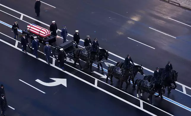 The flag-draped casket of former President Jimmy Carter travels in a horse-drawn caisson from the U.S. Navy Memorial to the Capitol to lie in state in Washington, Tuesday, Jan. 7, 2025. Carter died Dec. 29 at the age of 100. (AP Photo/Mark Schiefelbein, Pool)