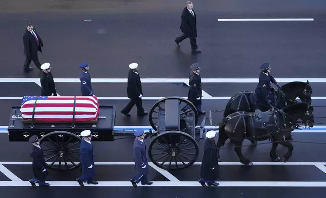 The flag-draped casket of former President Jimmy Carter travels by a horse-drawn caisson to the Capitol to lie in state in Washington, Tuesday, Jan. 7, 2025. Carter died Dec. 29 at the age of 100. (AP Photo/Mark Schiefelbein, Pool)