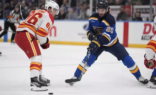 St. Louis Blues' Brandon Saad (20) reaches for a loose puck as Calgary Flames' Rory Kerins (86) defends during the second period of an NHL hockey game Tuesday, Jan. 14, 2025, in St. Louis. (AP Photo/Jeff Roberson)