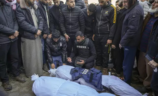 Colleagues and friends mourn over the body of freelance journalist Omar al-Derawi and other victims of overnight Israeli army strikes at multiple locations in central Gaza Strip, at Al-Aqsa Martyrs Hospital in Deir al-Balah, Friday, Jan. 3, 2025. According to Al-Aqsa Martyrs Hospital, 30 people, including 10 women and 7 children, were killed in several attacks overnight in central Gaza. (AP Photo/Abdel Kareem Hana)