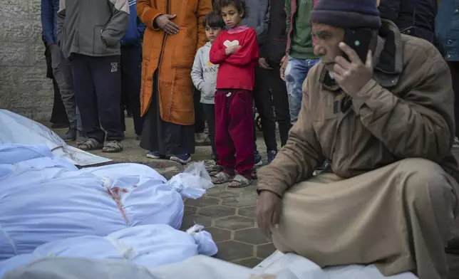 Children watch as the bodies of victims from overnight Israeli army strikes at multiple locations in the central Gaza Strip are laid together for funeral prayers, at Al-Aqsa Martyrs Hospital in Deir al-Balah, Friday, Jan. 3, 2025. According to Al-Aqsa Martyrs Hospital, 30 people, including 10 women and 7 children, were killed in several attacks overnight in central Gaza. (AP Photo/Abdel Kareem Hana)