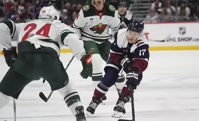 Colorado Avalanche center Parker Kelly, right, passes the puck as Minnesota Wild defensemen Zach Bogosian, left, and Jon Merrill cover in the first period of an NHL hockey game Monday, Jan. 20, 2025, in Denver. (AP Photo/David Zalubowski)