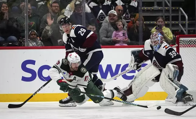 Minnesota Wild left wing Marcus Foligno, front left, passes the puck as Colorado Avalanche center Nathan MacKinnon, back left, and goaltender Mackenzie Blackwood defend in the first period of an NHL hockey game Monday, Jan. 20, 2025, in Denver. (AP Photo/David Zalubowski)