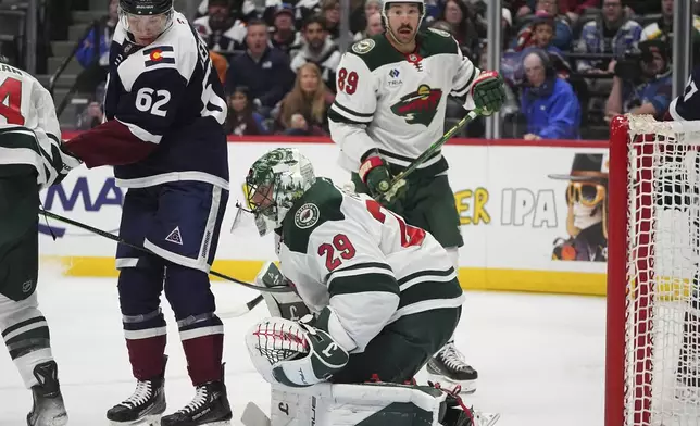 Minnesota Wild goaltender Marc-Andre Fleury, front, makes a save of a redirected shot off the stick of Colorado Avalanche left wing Artturi Lehkonen, back left, as Minnesota center Frederick Gaudreau looks on in the first period of an NHL hockey game Monday, Jan. 20, 2025, in Denver. (AP Photo/David Zalubowski)