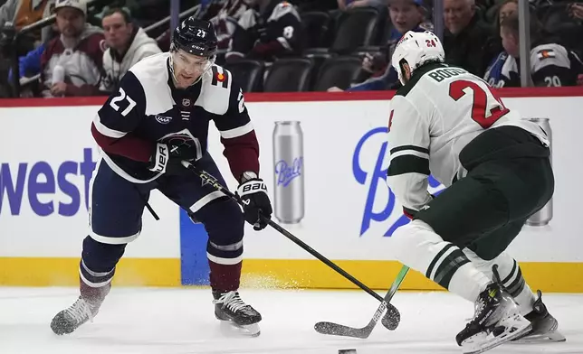 Colorado Avalanche left wing Jonathan Drouin, left, fights for control of the puck with Minnesota Wild defenseman Zach Bogosian in the first period of an NHL hockey game Monday, Jan. 20, 2025, in Denver. (AP Photo/David Zalubowski)