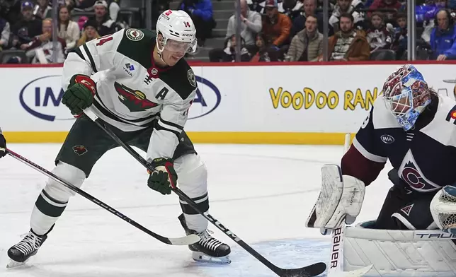 Minnesota Wild center Joel Eriksson Ek, left, redirects the puck at Colorado Avalanche goaltender Mackenzie Blackwood in the second period of an NHL hockey game Monday, Jan. 20, 2025, in Denver. (AP Photo/David Zalubowski)