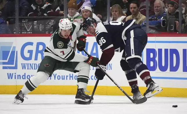 Minnesota Wild defenseman Brock Faber, left, knocks the puck away from Colorado Avalanche right wing Mikko Rantanen, right, in the second period of an NHL hockey game Monday, Jan. 20, 2025, in Denver. (AP Photo/David Zalubowski)