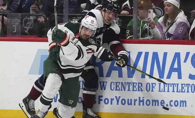 Minnesota Wild left wing Marcus Foligno, front, clears the puck after checking Colorado Avalanche left wing Artturi Lehkonen in the second period of an NHL hockey game Monday, Jan. 20, 2025, in Denver. (AP Photo/David Zalubowski)
