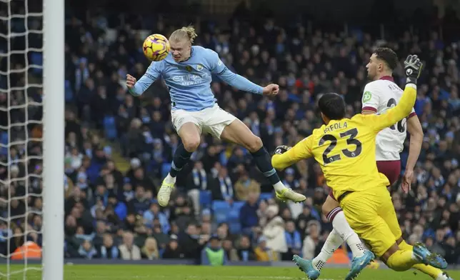 Manchester City's Erling Haaland, left, scores his side's 2nd goal against West Ham during a English Premier League soccer match at Etihad stadium in Manchester, England, Saturday, Jan. 4, 2025. (AP Photo/Ian Hodgson)