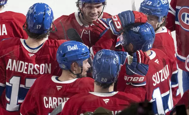 Montreal Canadiens center Nick Suzuki (14) celebrates with teammates after scoring the winning goal against the Vancouver Canucks in overtime NHL hockey game action in Montreal, Monday, Jan. 6, 2025. (Ryan Remiorz/The Canadian Press via AP)