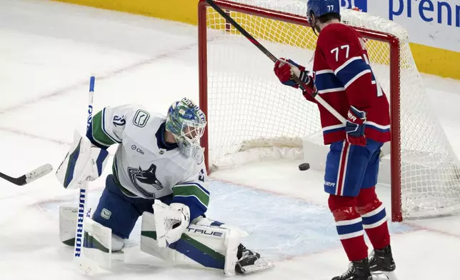 Montreal Canadiens center Kirby Dach (77) looks on as a shot by teammate Nick Suzuki beats Vancouver Canucks goaltender Kevin Lankinen, left, for the winning goal during overtime NHL hockey game action in Montreal, Monday, Jan. 6, 2025. (Ryan Remiorz/The Canadian Press via AP)