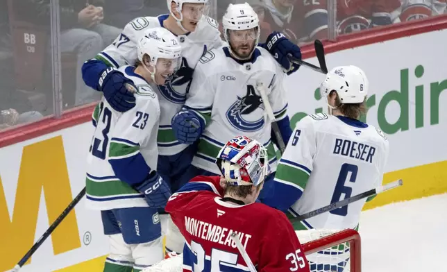 Vancouver Canucks' Jonathan Lekkerimaki, (23) celebrates with teammates after scoring the third goal against Montreal Canadiens goaltender Sam Montembeault (35) during second-period NHL hockey game action in Montreal, Monday, Jan. 6, 2025. (Ryan Remiorz/The Canadian Press via AP)